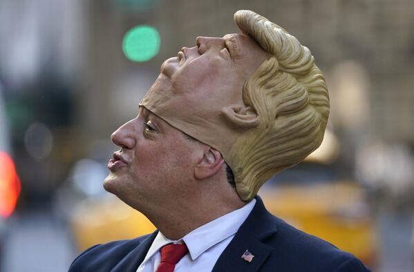 Un hombre llevando una máscara de Donald Trump frente a la Torre Trump en Nueva York, donde se congregó una multitud para esperar la llegada del expresidente estadounidense. - Sputnik Mundo