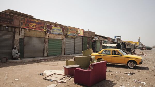 Un hombre sentado junto a unas tiendas cerradas en Jartum, Sudán, el lunes 17 de abril de 2023 - Sputnik Mundo