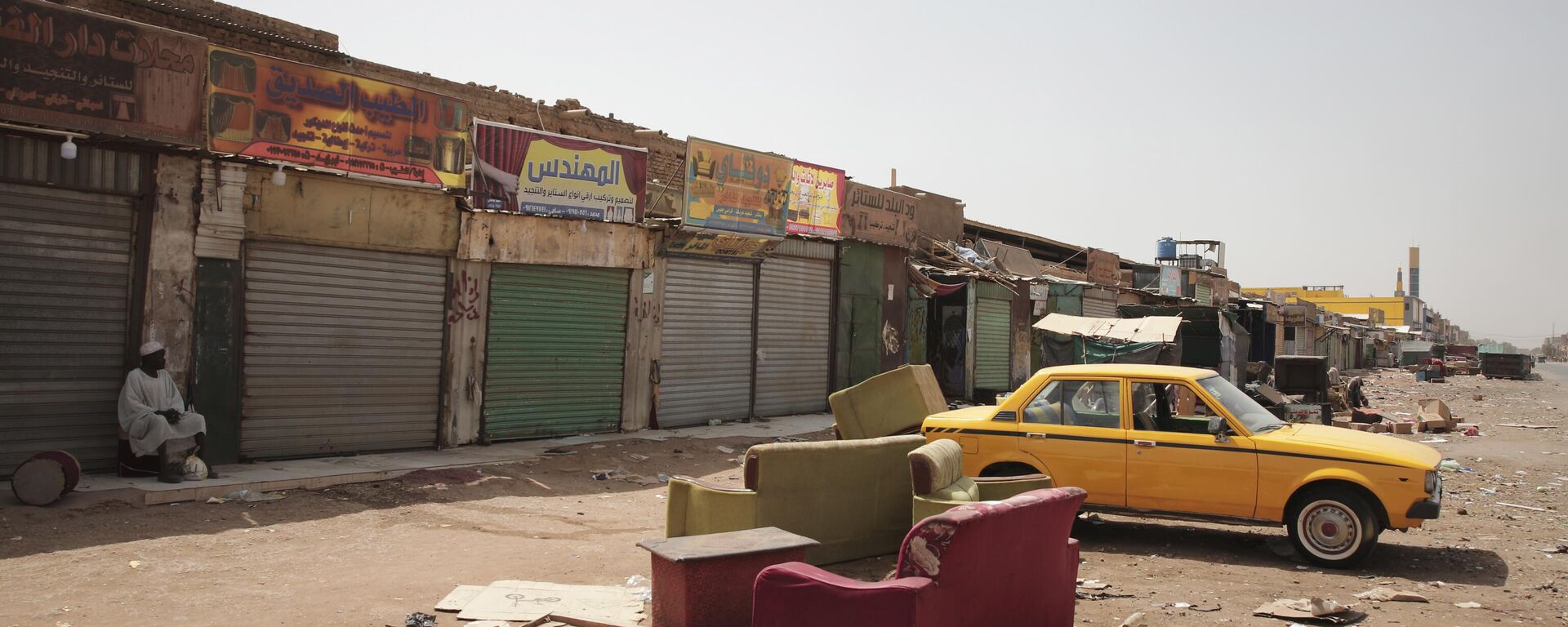 Un hombre sentado junto a unas tiendas cerradas en Jartum, Sudán, el lunes 17 de abril de 2023 - Sputnik Mundo, 1920, 17.04.2023