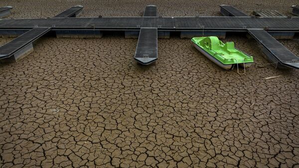 Зеленый катамаран на треснувшей земле в результате засухи в порту водохранилища Сау в Испании  - Sputnik Mundo