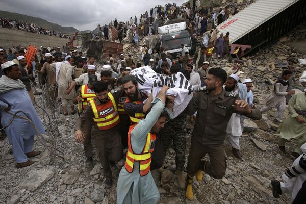 Rescatistas y voluntarios transportan el cadáver de un hombre hallado durante la retirada de escombros en el lugar donde se produjo un corrimiento de tierras en la ciudad de Torkham, cerca de la frontera entre Pakistán y Afganistán. - Sputnik Mundo