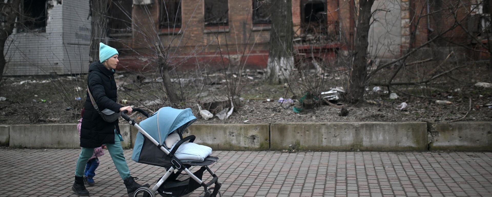 Una mujer con un cochecito de bebé en una calle de Mariúpol - Sputnik Mundo, 1920, 23.04.2023
