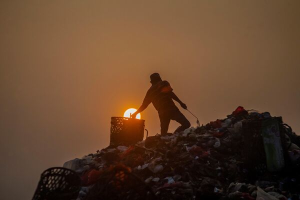 Un hombre busca objetos para revender tras la descarga de camiones de basura en un vertedero cerca de Bogor, Indonesia. - Sputnik Mundo