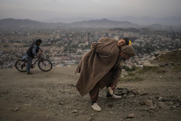 Un anciano y su hijo pequeño despejan una carretera en Kabul, Afganistán. - Sputnik Mundo