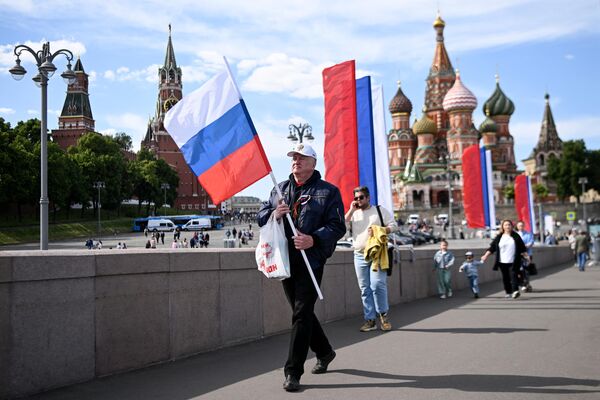 El Día de Rusia se considera fiesta oficial en el país.En la foto: un hombre lleva una bandera nacional rusa al salir del concierto patriótico en la plaza Roja, cerca del Kremlin. - Sputnik Mundo