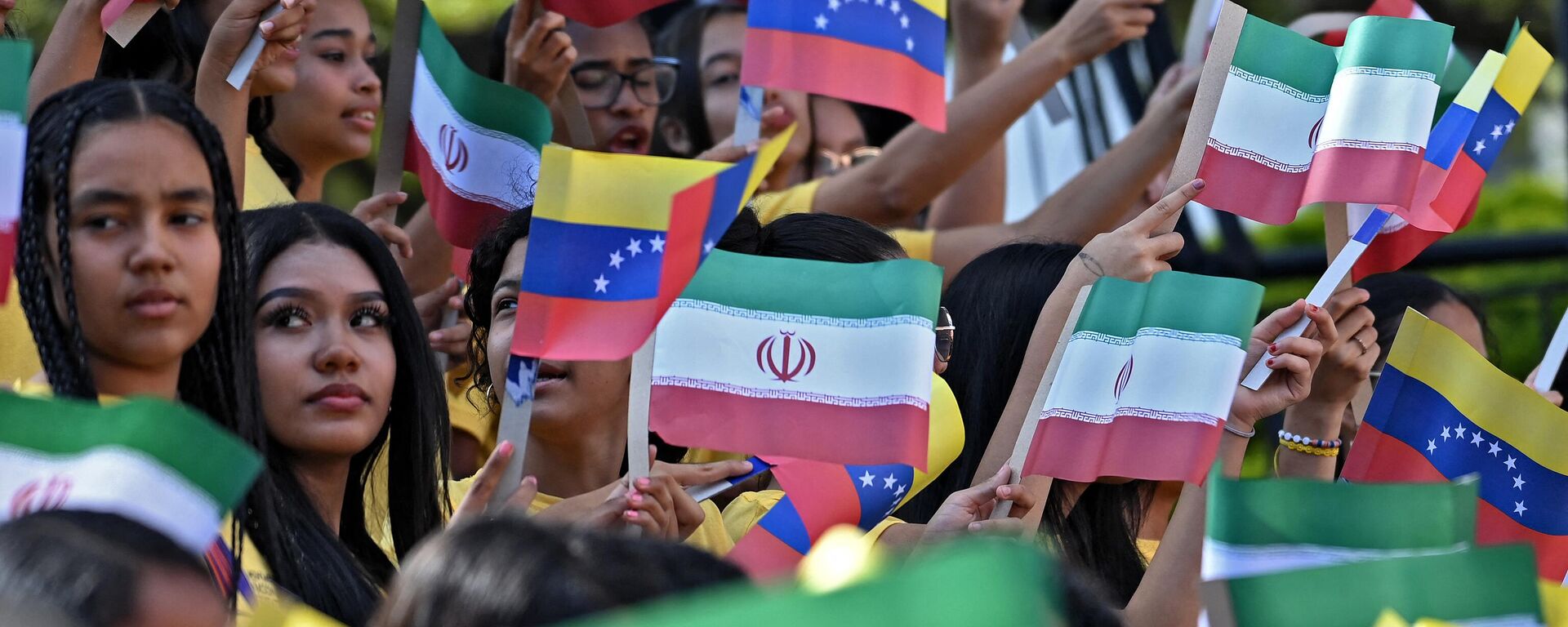 Mujeres jóvenes ondean banderas nacionales de Venezuela e Irán durante la llegada del presidente iraní Ebrahim Raisi al Palacio Presidencial de Miraflores, en Caracas, el 12 de junio de 2023.   - Sputnik Mundo, 1920, 14.06.2023