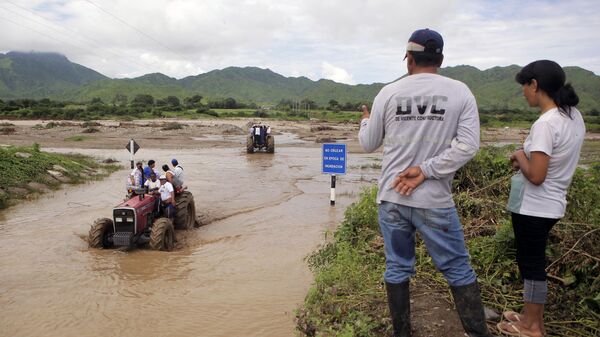 Habitantes de las afueras de la ciudad de Chiclayo, 770 kilómetros al norte de Lima, utilizan un tractor para cruzar la crecida del río Zana, después de fenómeno El Niño.  - Sputnik Mundo