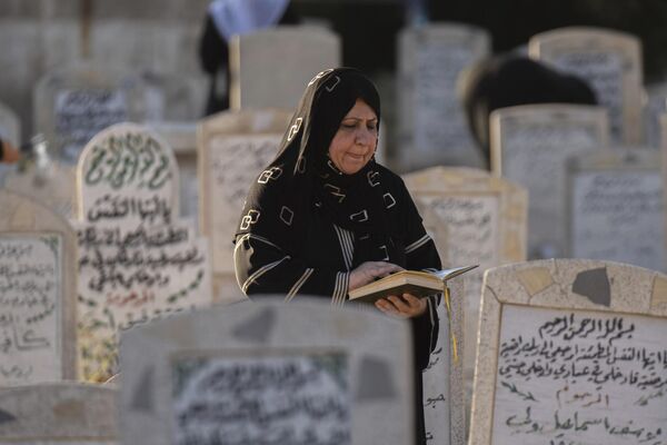 En este día se recomienda visitar el cementerio para pasar tiempo con los familiares fallecidos y ordenar sus tumbas. En la foto: una mujer musulmana lee el Corán en la tumba de un familiar en el cementerio de Ghazali, en la capital iraquí, Bagdad. - Sputnik Mundo