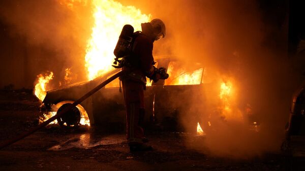 Un bombero extingue el fuego tras las protestas en Francia por asesinato de joven de 17 años por la policía - Sputnik Mundo