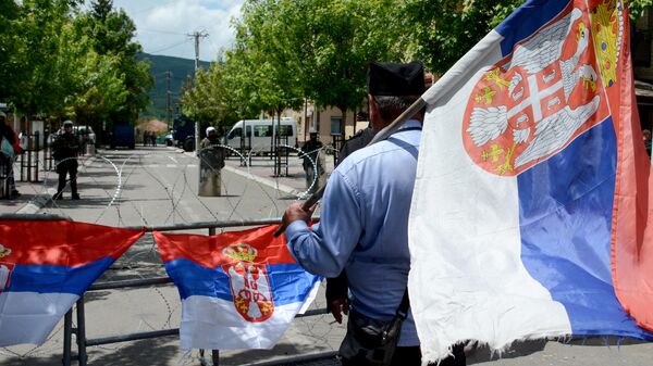 Un hombre con una bandera serbia mira de pie frente a los soldados de la Fuerza Internacional de Seguridad en Kosovo (KFOR), el norte de Kosovo, el 31 de mayo de 2023 - Sputnik Mundo