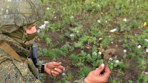 Un militar muestra un fragmento de una mina Lepestok cerca del pueblo de Spórnoye, república popular de Donetsk  - Sputnik Mundo
