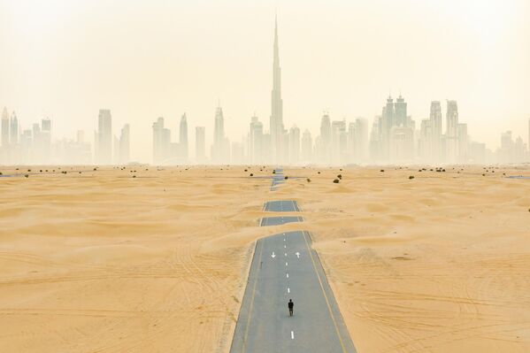 En Dubái, primero se construyen carreteras y luego edificios. Por lo tanto, hay varios lugares donde la carretera está trazada, pero junto a ella no hay edificios. Una de estas vías, con cruce en los alrededores de Dubái, está gradualmente cubierta de arena. - Sputnik Mundo