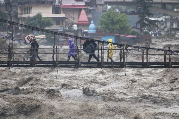 Varias personas caminan por un puente sobre el río Beas que se ha desbordado tras las fuertes lluvias en Kullu, Himachal Pradesh, la India. - Sputnik Mundo