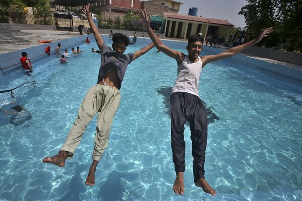 Dos jóvenes saltan a una piscina en Peshawar, Pakistán, donde el calor alcanzó los 39 grados. - Sputnik Mundo
