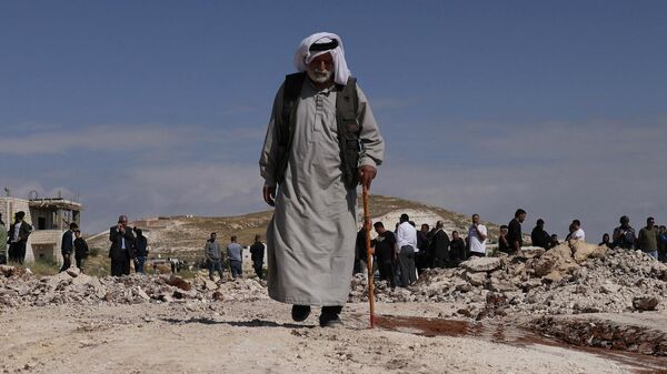 Un anciano palestino se aleja de la multitud mientras excavadoras del Ejército israelí derriban una escuela que, según ellos, fue construida sin permiso en la aldea de Jabbet al-Dhib, al este de Belén, en la Cisjordania ocupada, el 7 de mayo de 2023. - Sputnik Mundo