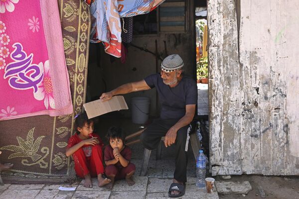 Una ola de calor anormal está &quot;quemando&quot; gran parte de nuestro planeta.En la foto: un padre salva a sus hijos del calor agitándoles un trozo de cartón en la ciudad de Gaza, Palestina. - Sputnik Mundo