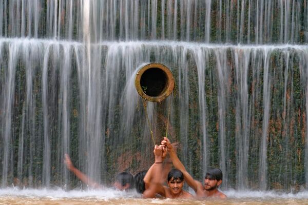 Jóvenes pakistaníes se refrescan en una cascada de Islamabad, donde las temperaturas alcanzan los 36 grados. - Sputnik Mundo