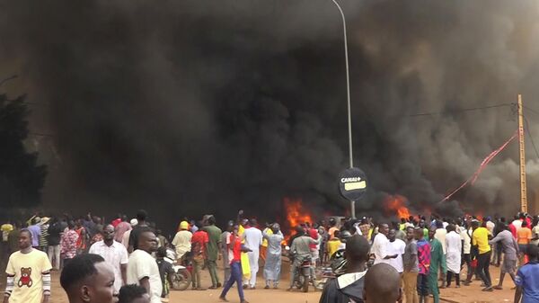 Con la sede del partido gobernante ardiendo por la espalda, partidarios de los soldados amotinados se manifiestan en Niamey, Níger, el jueves 27 de julio de 2023 - Sputnik Mundo