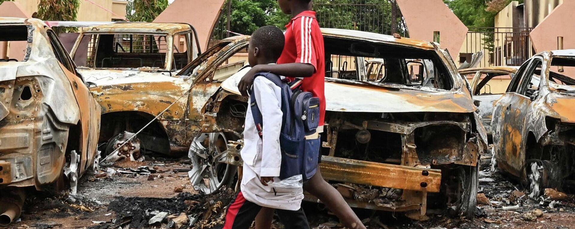 Niños caminan junto a unos coches quemados frente a la sede del Partido Nigerino para la Democracia y el Socialismo del presidente Bazoum, en Niamey, el 7 de agosto de 2023.  - Sputnik Mundo, 1920, 18.08.2023