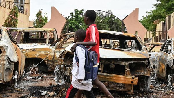 Niños caminan junto a unos coches quemados frente a la sede del Partido Nigerino para la Democracia y el Socialismo del presidente Bazoum, en Niamey, el 7 de agosto de 2023 - Sputnik Mundo