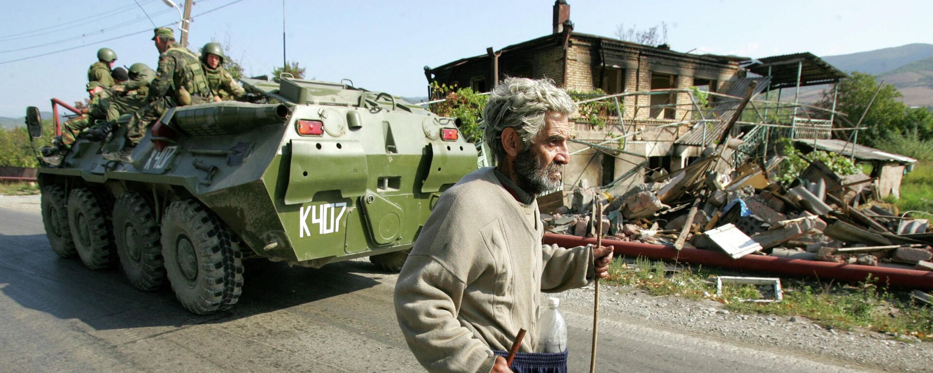 El residente pasa junto a tropas rusas en un vehículo blindado de transporte de tropas y edificios destruidos en Kurta, 20 kms al norte de Tsjinvali, Osetia del Sur, el 5 de septiembre de 2008. - Sputnik Mundo, 1920, 08.08.2023