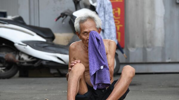 Un hombre se seca la cara con una toalla durante un día caluroso en un distrito residencial en Seúl. - Sputnik Mundo