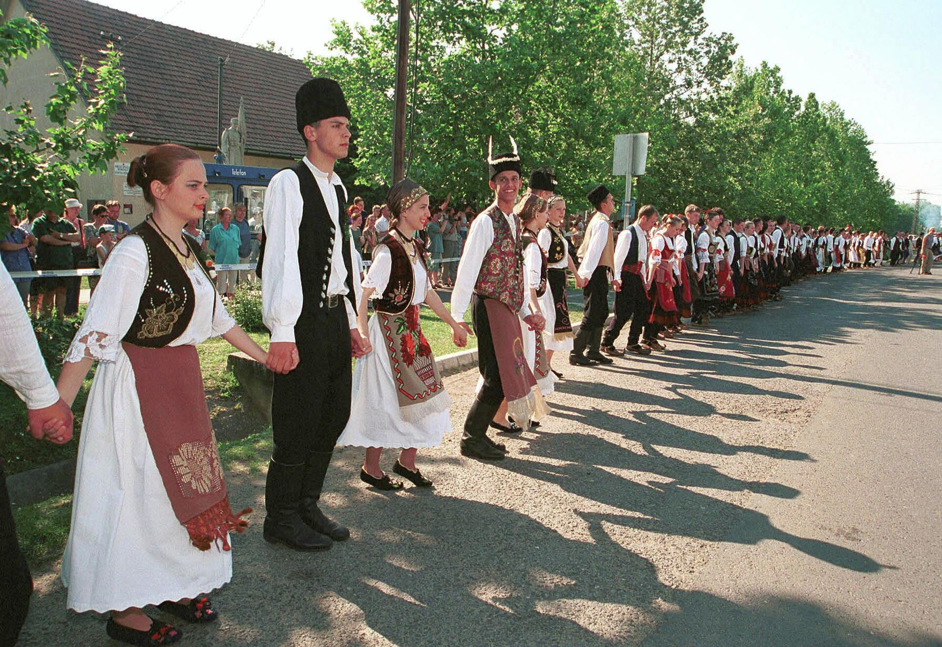 Bailarines folclóricos, vestidos con trajes tradicionales serbios, interpretan la danza folclórica serbia Kolo en la calle principal de Deszk, a unos 175 km al sur de Budapest, Hungría - Sputnik Mundo, 1920, 09.08.2023