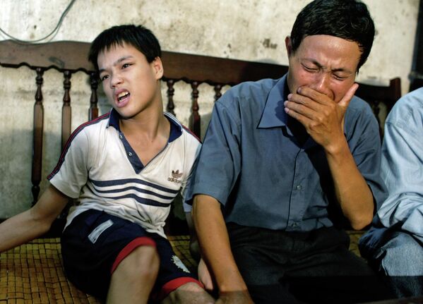 Nguyen Van Quy, de 49 años, con su hijo de 17 años, Nguyen Quang Trung, que nació con discapacidades físicas y mentales debido a la exposición de su padre al agente naranja durante la guerra, Hai Phong, Vietnam, 2004. - Sputnik Mundo