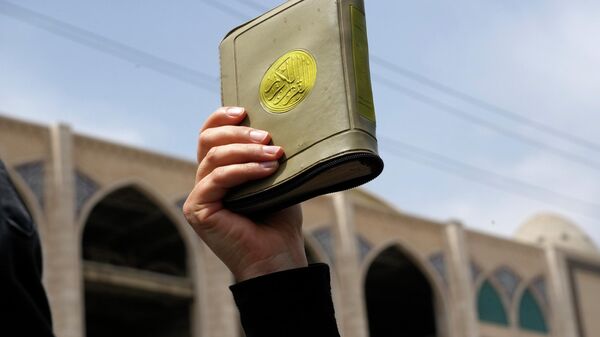Un fiel sostiene una copia del Corán durante una protesta contra Suecia el pasado 21 de julio en Teherán, Irán. - Sputnik Mundo
