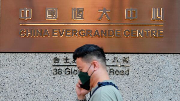 Un hombre pasa por delante de la entrada de la sede de China Evergrande Group en Hong Kong  - Sputnik Mundo