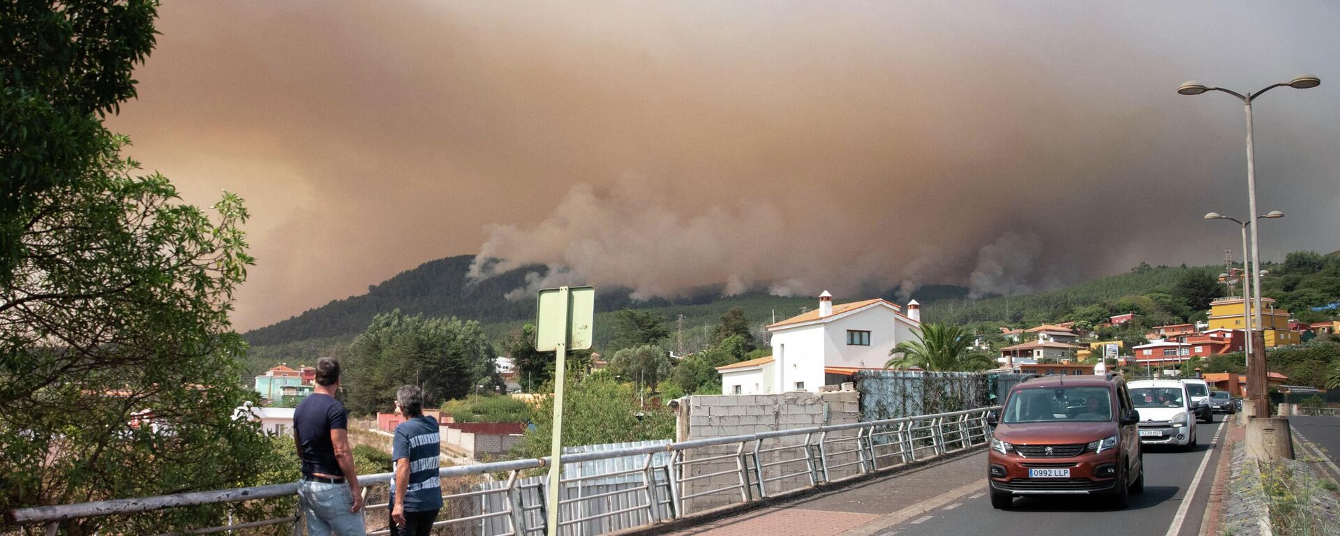 Dos personas en Nuestra Señora del Rosario, el 17 de agosto de 2023, observan enormes nubes de humo procedentes de un incendio forestal en Tenerife  - Sputnik Mundo, 1920, 18.08.2023