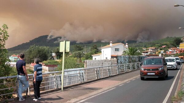 Dos personas en Nuestra Señora del Rosario, el 17 de agosto de 2023, observan enormes nubes de humo procedentes de un incendio forestal en Tenerife - Sputnik Mundo