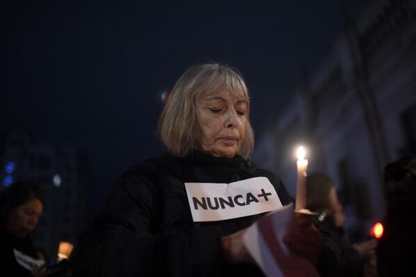 Una mujer sostiene una vela encendida y un cartel en el que se lee &quot;Nunca más&quot; mientras participa en una marcha de mujeres alrededor del Palacio de la Moneda. - Sputnik Mundo