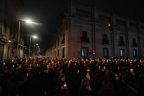Activistas por los derechos de las mujeres sostienen velas durante una vigilia por las víctimas de la dictadura del general Augusto Pinochet mientras caminan alrededor del palacio presidencial de La Moneda, en Santiago de Chile. - Sputnik Mundo