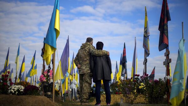 Los padres de un soldado ucraniano en un cementerio durante el Día de los Defensores de Ucrania en Járkov, Ucrania, el 14 de octubre de 2022 - Sputnik Mundo