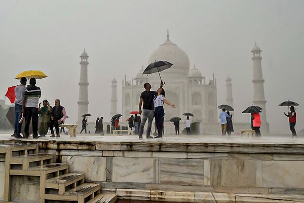 Turistas bajo paraguas posan para fotos mientras visitan el Taj Mahal durante un aguacero en la ciudad india de Agra, el 9 de octubre de 2022. - Sputnik Mundo