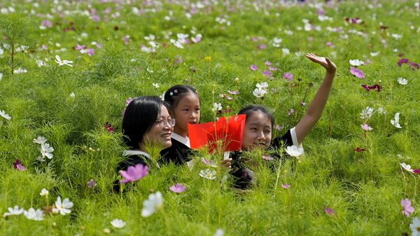 Una mujer y dos niñas en un campo de flores el Día Nacional del Campo en Hangzhou, China. - Sputnik Mundo