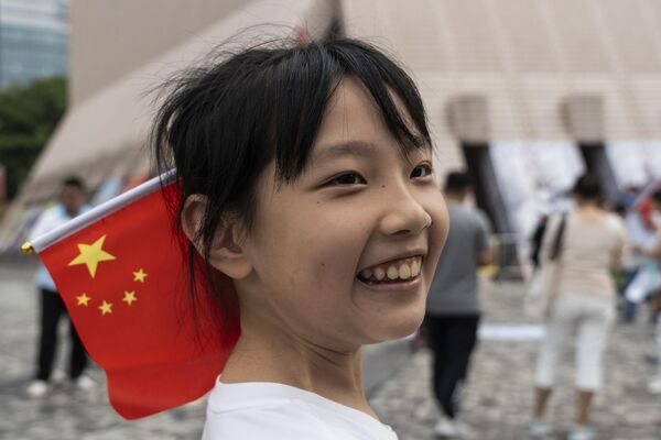 Desde 1999, el día de la fundación de China se celebra durante una semana, lo que se convirtió en un período de descanso para promover el turismo. Con el tiempo, éste se convirtió en una tradición nacional china y la propia festividad en una de las favoritas del país. En la foto: una niña con la bandera nacional china en el barrio de Tsim Sha Tsui, Hong Kong. - Sputnik Mundo