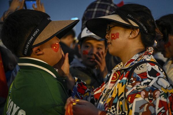 La fiesta en honor de la fundación de la República Popular China es un momento en el que la unidad y la cohesión del pueblo chino se hacen sentir especialmente. En estas fechas, los chinos envían &quot;Guo Qing Jie Kuai Le!&quot; (&quot;¡Feliz día de la fundación!&quot;) a sus familiares y amigos. En la foto: Asistentes a la ceremonia de izado de la bandera nacional en la plaza de Tiananmén de Pekín. - Sputnik Mundo