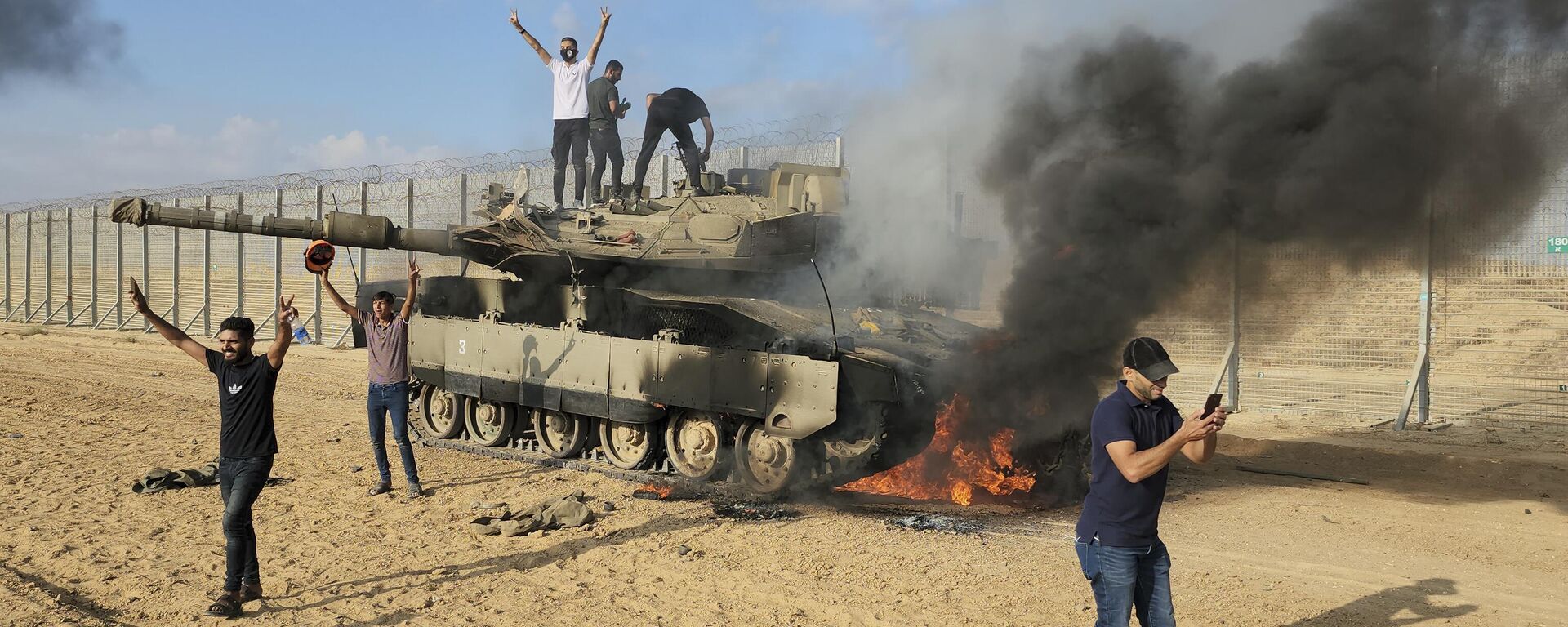 Palestinos celebrando junto a un tanque israelí destruido en la valla de la Franja de Gaza - Sputnik Mundo, 1920, 07.10.2023