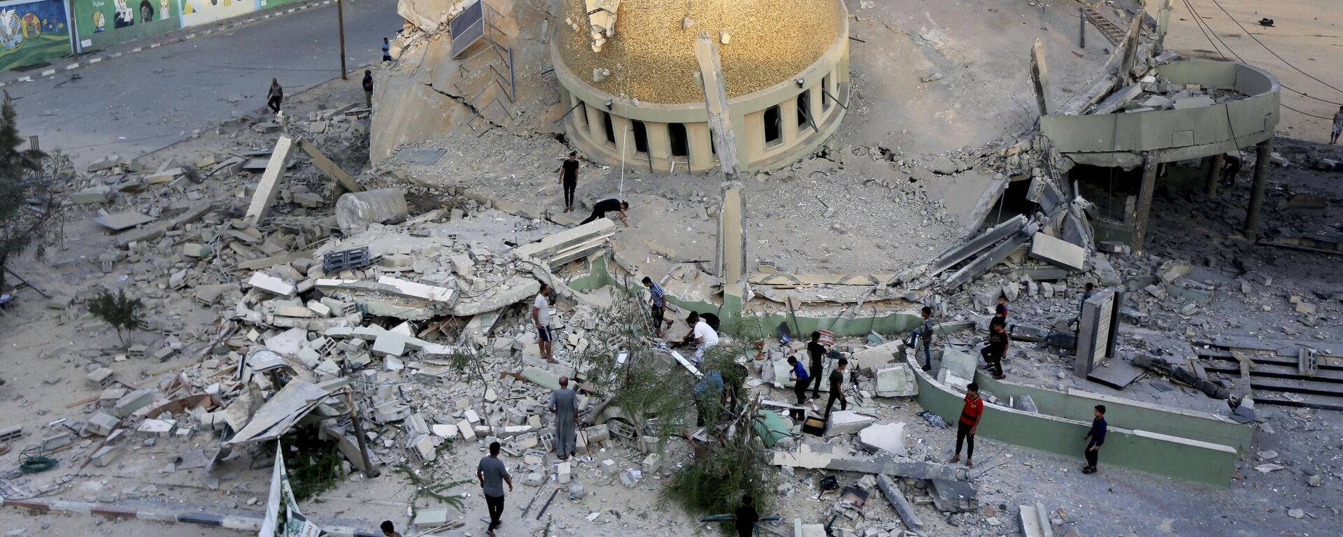 Un grupo de personas frente a una mezquita destruida por un ataque aéreo israelí en Jan Younis, Franja de Gaza, el domingo 8 de octubre de 2023. - Sputnik Mundo, 1920, 08.10.2023