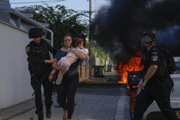 Agentes de Policía ayudan a una mujer y a su hija a abandonar el lugar de un ataque con cohetes de Hamás en Ascalón, en el sur de Israel. - Sputnik Mundo
