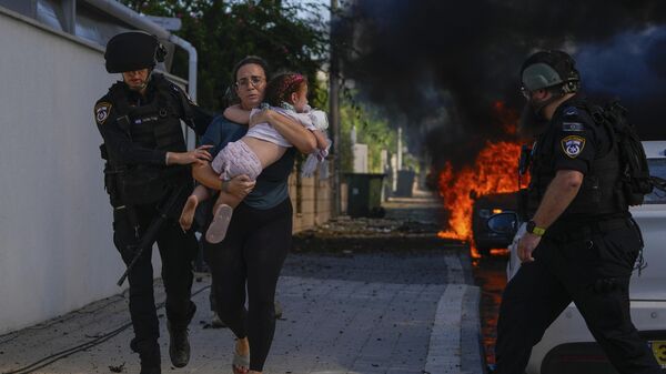 La policía evacua a una mujer y a un niño de un lugar alcanzado por un cohete lanzado desde la Franja de Gaza en Ascalón, en el sur de Israel. - Sputnik Mundo