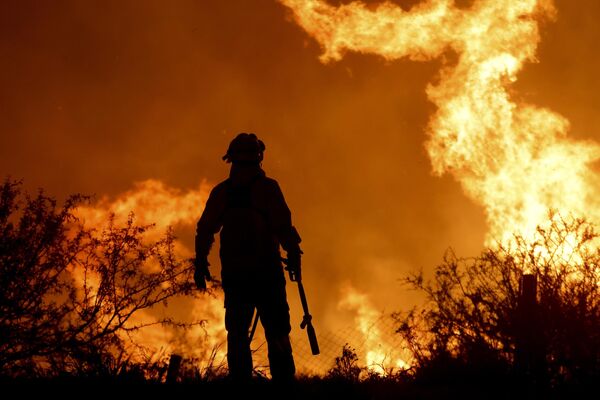 Un bombero lucha contra el incendio forestal en el barrio de Villa Carlos Paz, Argentina. - Sputnik Mundo