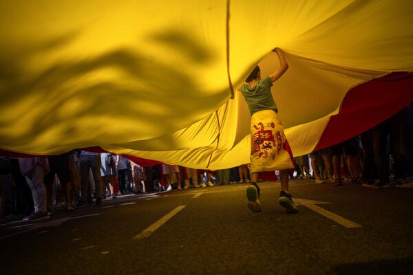 Un niño bajo una enorme bandera española durante una protesta contra una posible amnistía para los políticos separatistas catalanes en el centro de Barcelona, España. - Sputnik Mundo