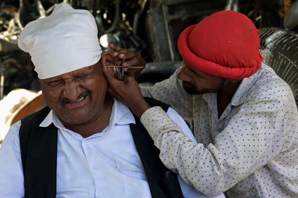 Un vendedor ambulante limpia la oreja de un cliente a un lado de la carretera en Amritsar, Punjab, la India. - Sputnik Mundo