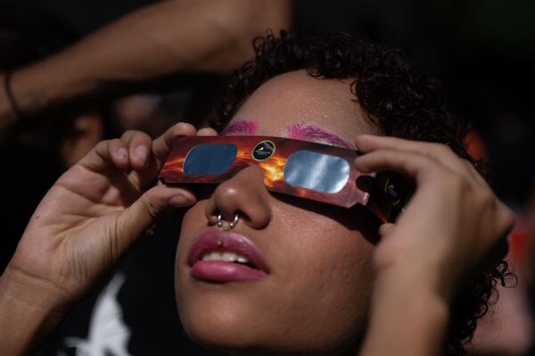 El próximo eclipse solar anular en esta parte del mundo será visible en 2046. En la foto: una mujer mira desde Caracas, Venezuela - Sputnik Mundo