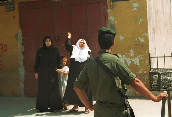 Una anciana palestina grita maldiciones a los militares israelíes tras la detención de su hijo en la Franja de Gaza, mayo de 1990. - Sputnik Mundo