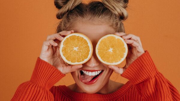Una joven con una fruta de naranja (referencial) - Sputnik Mundo