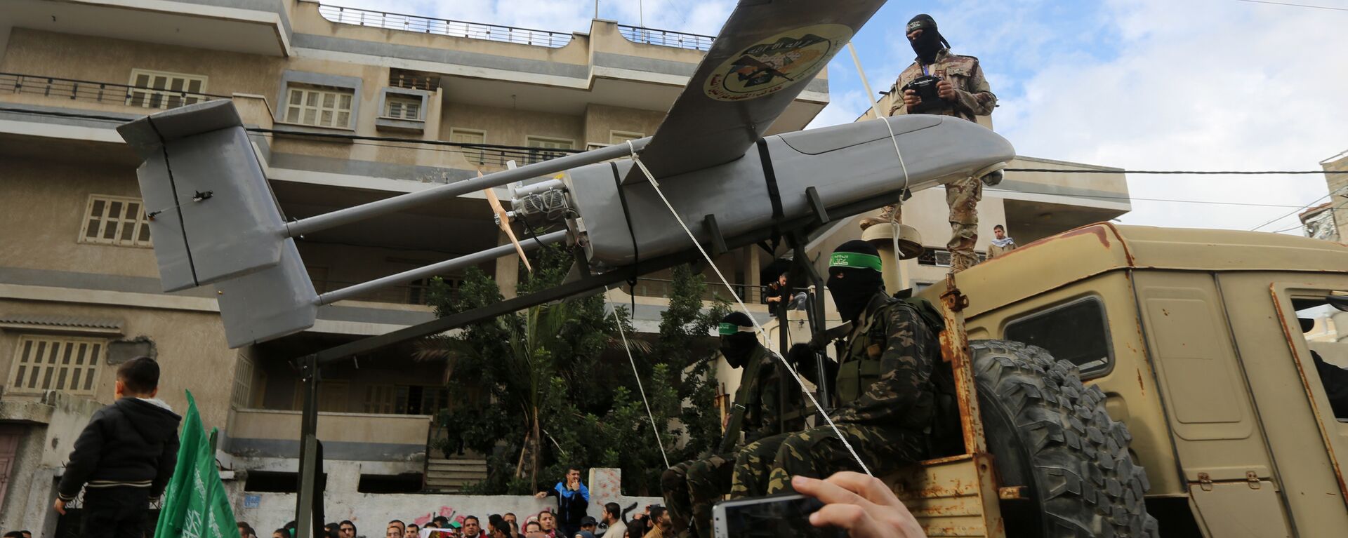 Militantes palestinos de las Brigadas Ezzedine al-Qassam, el brazo armado de Hamás, desembarcan un dron durante un desfile con motivo del 27 aniversario de la creación del movimiento islamista, el 14 de diciembre de 2014 en la ciudad de Gaza. - Sputnik Mundo, 1920, 26.10.2023